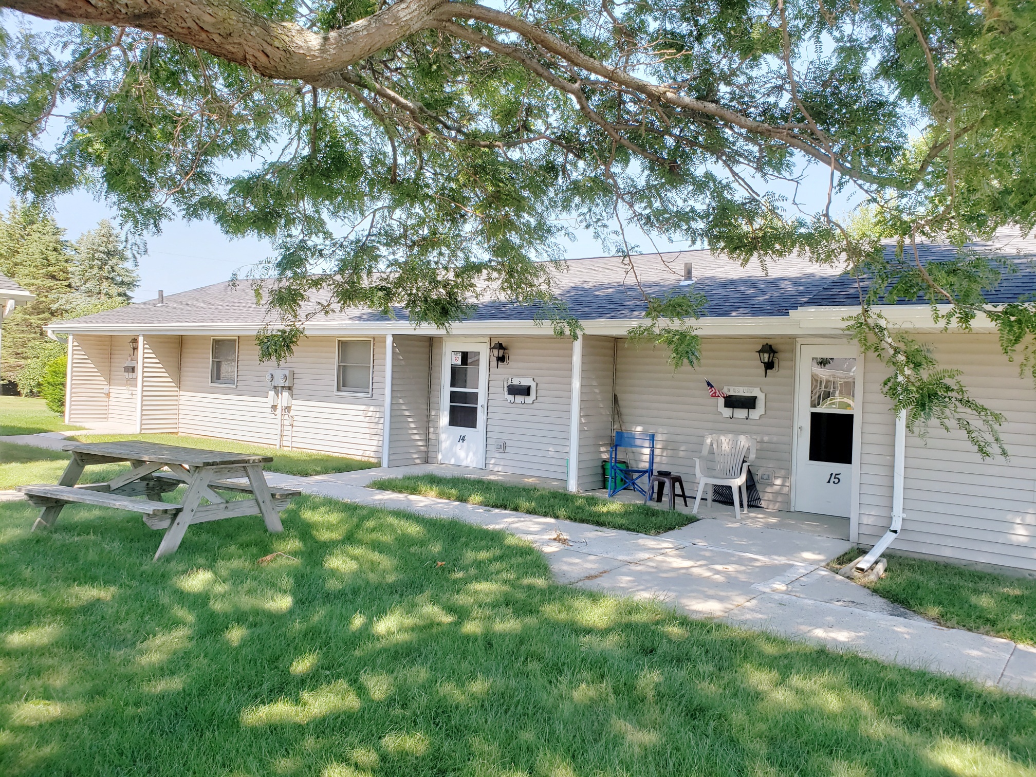 a small white house with a picnic table in the yard